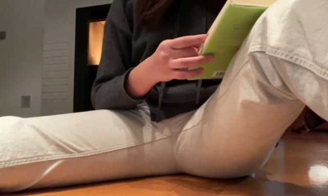 Girl peeing her jeans while reading a book